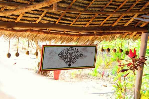A rustic hut with a thatched roof and a sign stating "There is no wifi in the forest but you will find a better connection." - Shanti Cafe & Yoga (Jambiani)