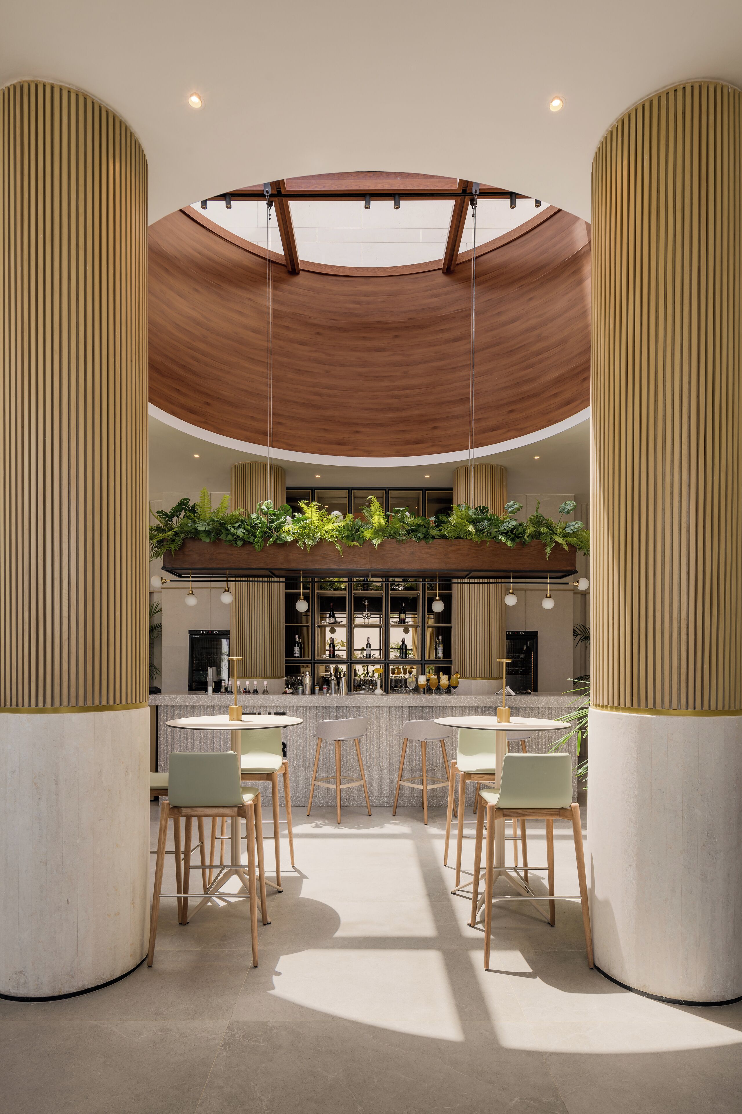 A modern interior with a central bar area, wooden columns, and a ceiling with a wooden slat design.