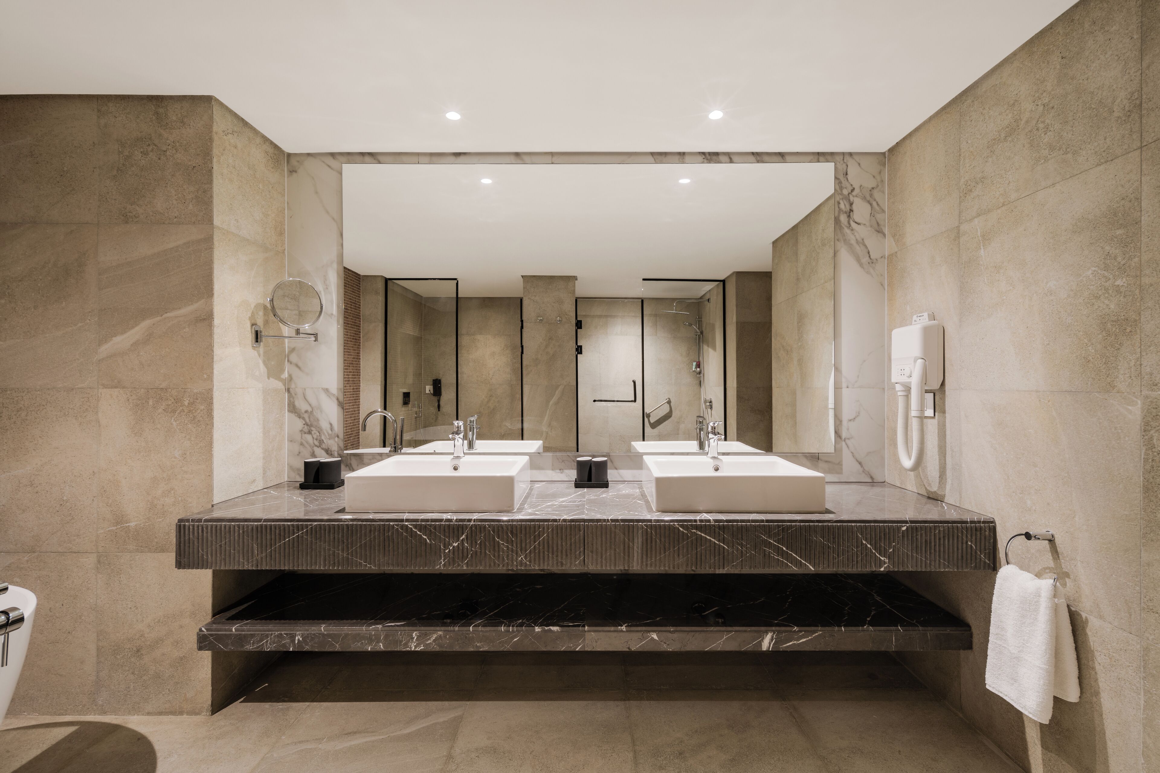 A modern bathroom with two sinks, a large mirror, and a towel rack.