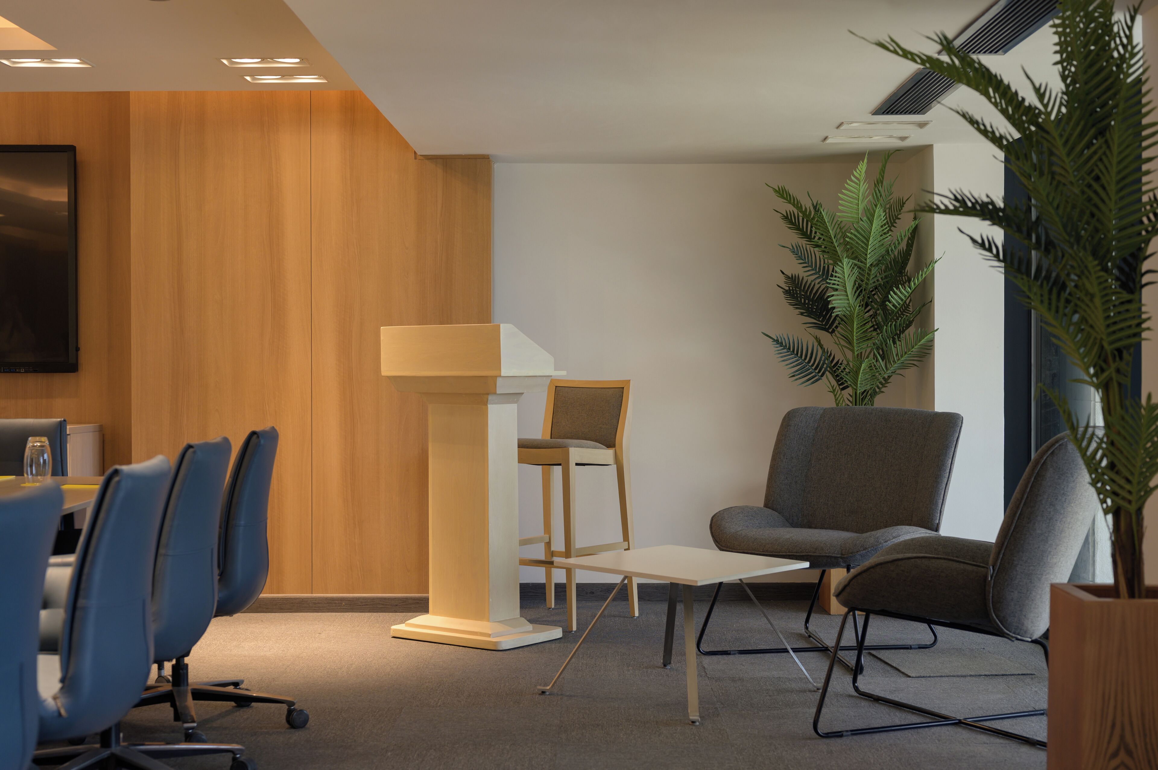 Een congreszaal met een spreekgestoelte, een tafel en meerdere stoelen.
