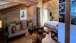 A cozy attic bedroom with a wooden ceiling, a bed, a sofa, and a table with decorative items. - Cosy Chalet With Balcony/terrace (Saanen)