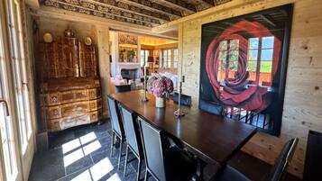 A dining area with a wooden table, chairs, and a large abstract painting.