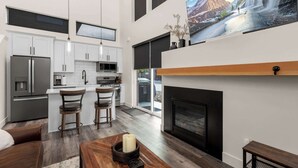 A modern kitchen with white cabinets, stainless steel appliances, and a large window. - Modern Mountain Townhouse at The Quarry (Whitefish)