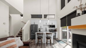 A modern kitchen with white cabinets, a central island, and a built-in oven. - Modern Mountain Townhouse at The Quarry (Whitefish)