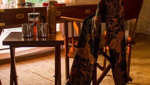 A cozy room with a wooden table, a chair, a lamp, and a window with curtains. - Umaria Safari Camp -Kanha National Park  (Bichhiya)