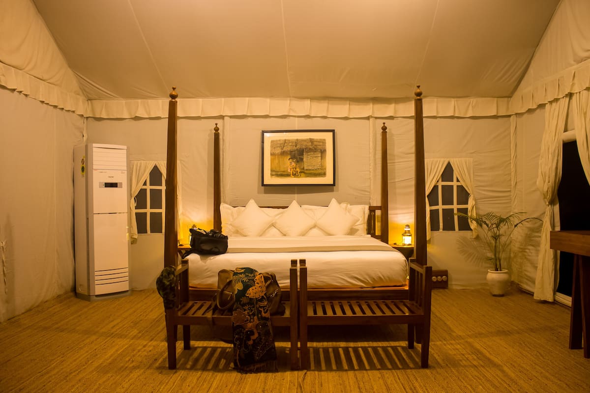Ein Bett mit Himmelbett und weißem Moschee, ein gerahmtes Bild darüber und eine h ölzerne Bank davor.