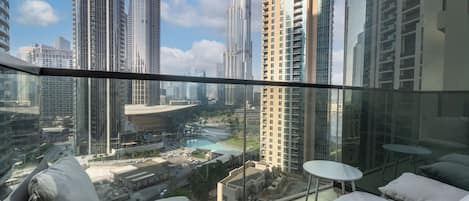 A high-rise apartment with a balcony, offering views of a cityscape and a swimming pool.