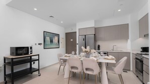 A modern kitchen with a dining area, featuring a refrigerator, stove, and a dining table set for six.