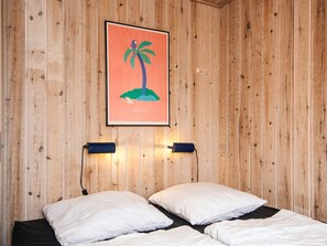 A room with wooden panel walls, a bed with white bedding, and a framed picture of a LEGO island. - 4 Person Holiday Park Home in Jelling (Jelling)