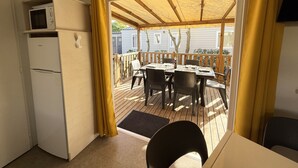 A compact kitchen with a microwave, a refrigerator, and a dining area with a table and chairs. - Mobile-home Camping Le Marisol - Torreilles-plage (Torreilles)