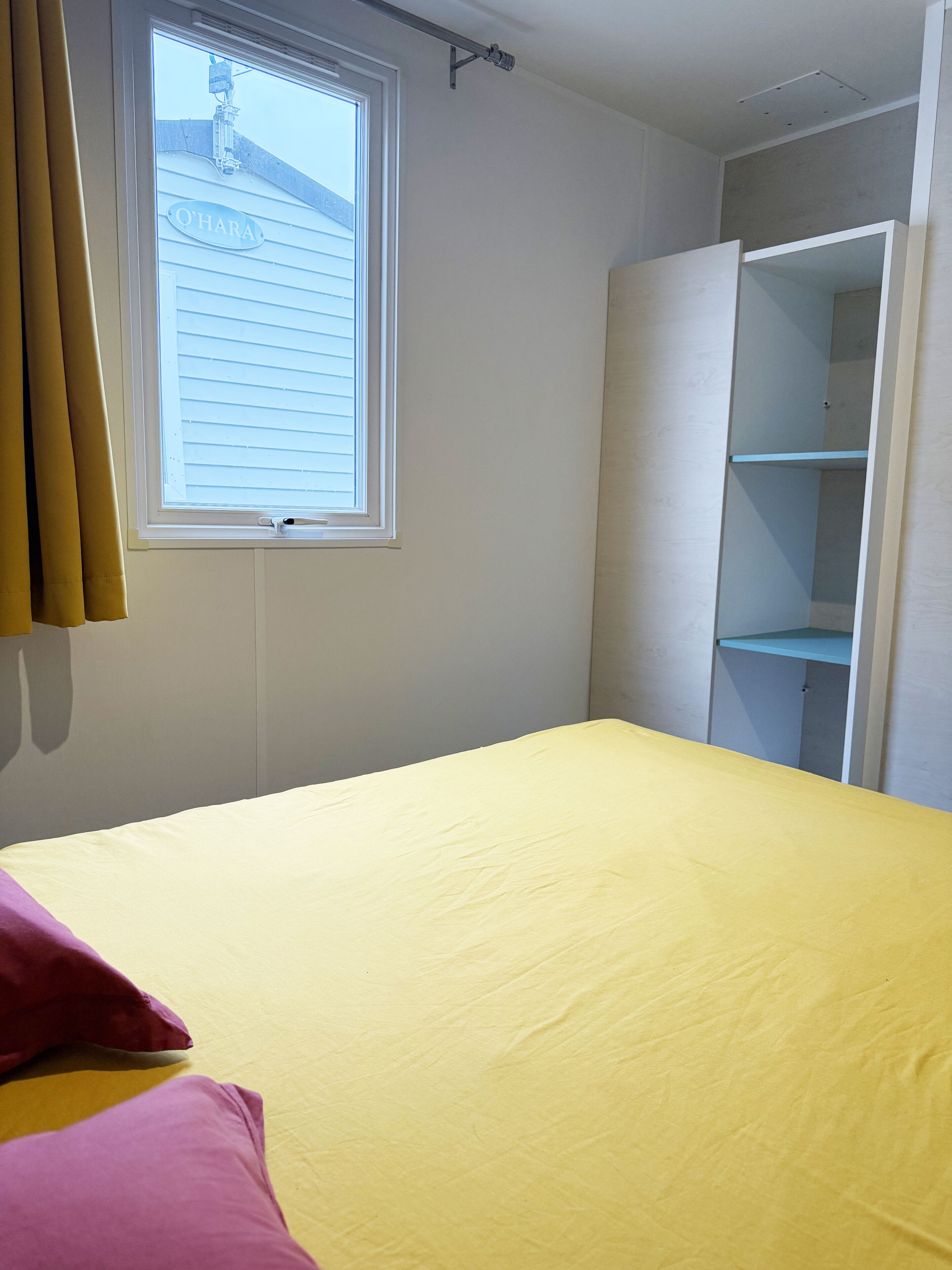 Ein Zimmer mit einem Bett, einem Fenster und einem Kleiderschrank.