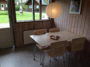 Un comedor con una mesa y sillas, una lámpara colgante y vistas al exterior.