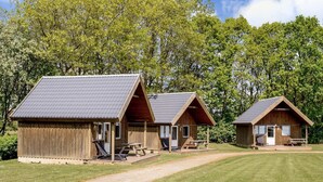 Two wooden cabins with pitched roofs, each featuring a porch and a picnic table. - 4 Person Holiday Park Home in Jelling (Jelling)