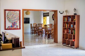 A room with a wooden dining table and chairs, a bookshelf, and a framed artwork on the wall. - Nature Kigali (Kigali)