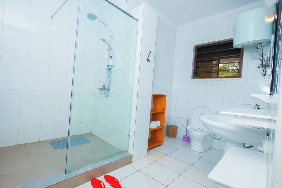 A modern bathroom with a glass-enclosed shower, a white sink, and a toilet.