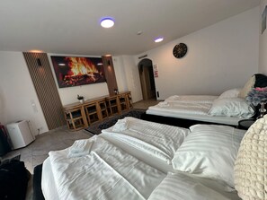 Ein Hotelzimmer mit zwei Betten, einem Fernseher, einer Uhr und einem Kamin.