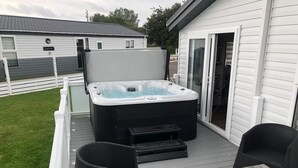 Un jacuzzi en una terraza con sillas de mimbre y una mesa.
