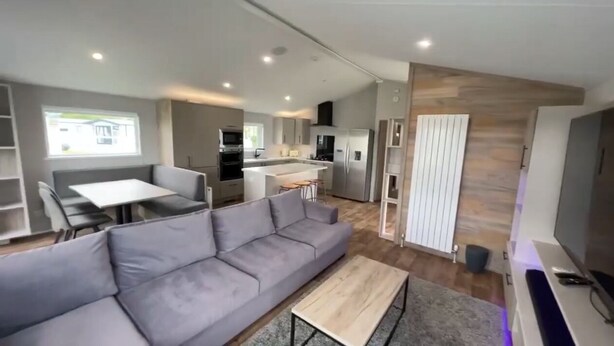 Una sala de estar moderna con un sofá gris, una mesa de centro de madera y un televisor.