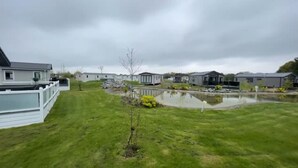Un barrio residencial con varias casas, un pequeño estanque y un césped cubierto de hierba.