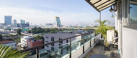 A balcony with a glass railing overlooking a cityscape with modern buildings.