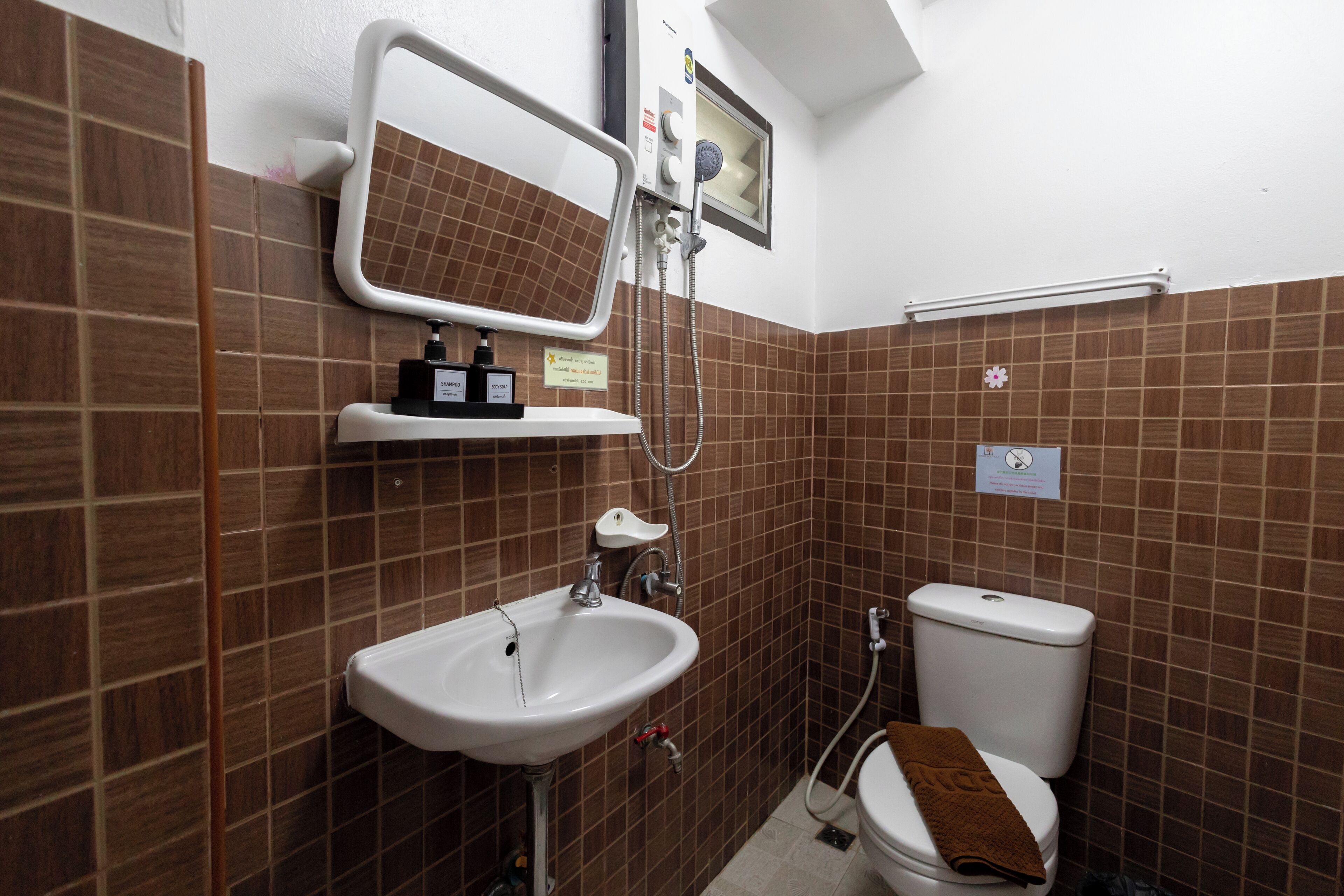 A bathroom with a sink, mirror, shower, and toilet.