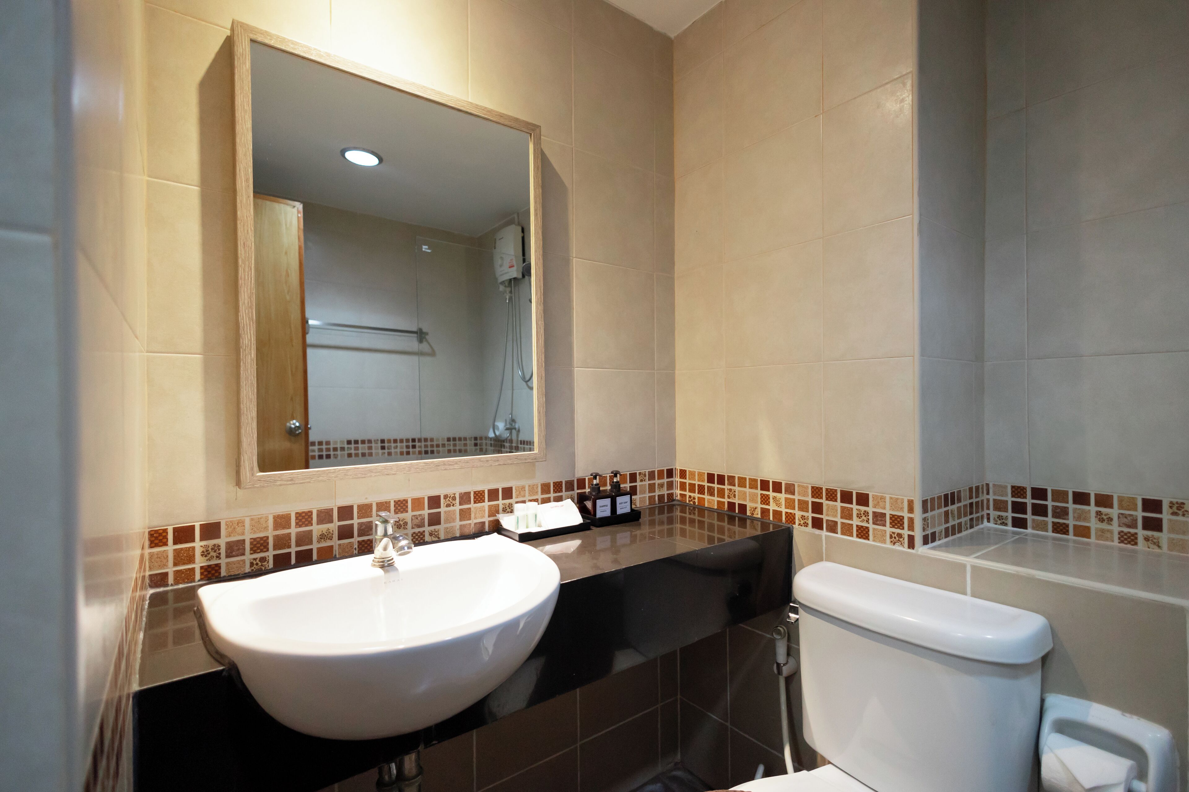 A bathroom with a white sink, a mirror, a toilet, and a shower area.