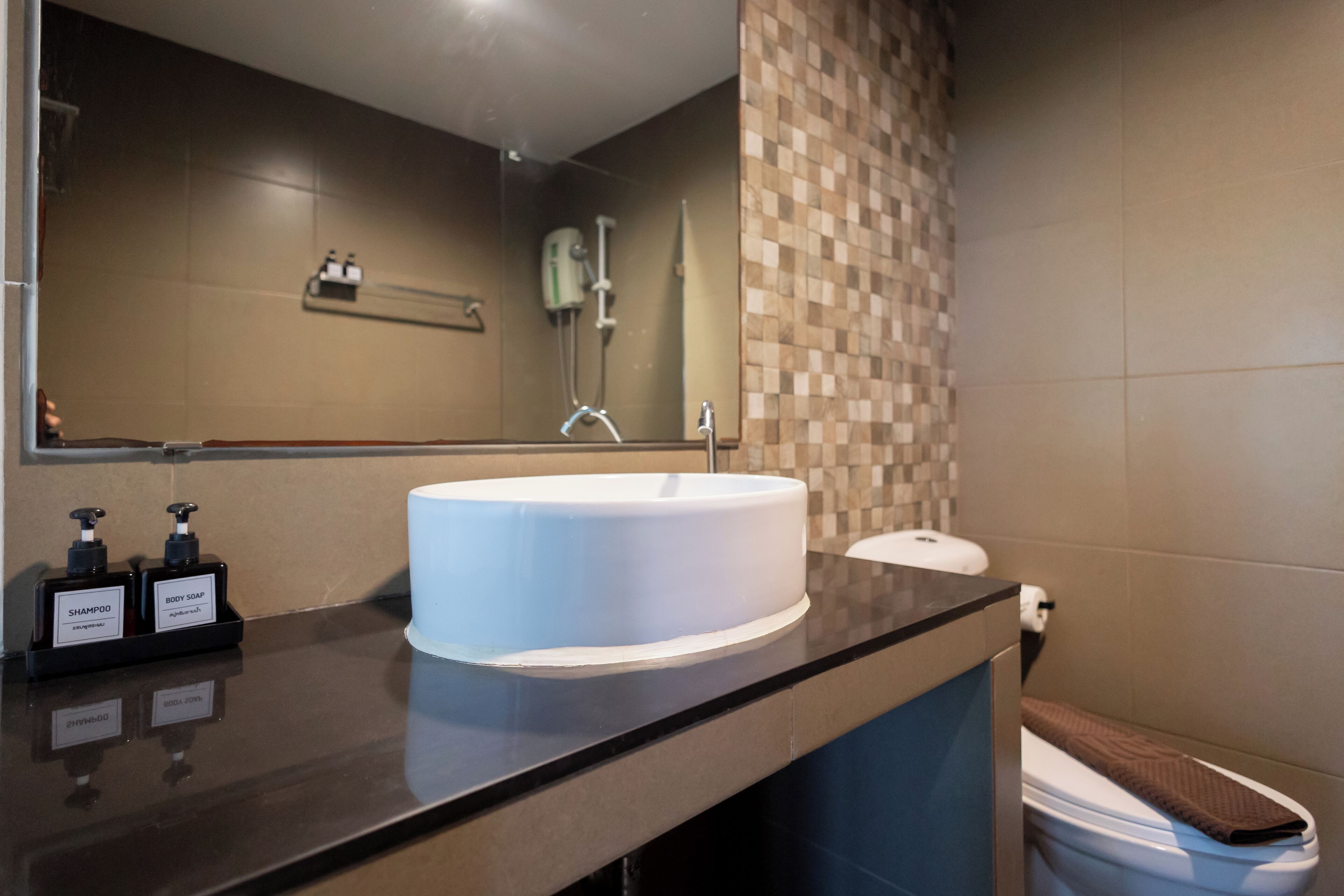 A modern bathroom with a large sink, a mirror, and toiletries on the counter.