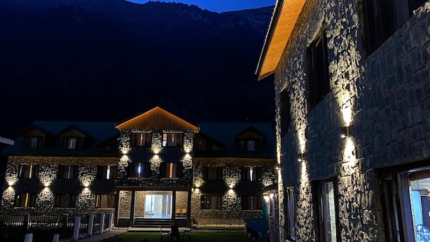A stone building with multiple windows and a well-lit entrance. - Hotel Mountview Sonamarg (Gund)