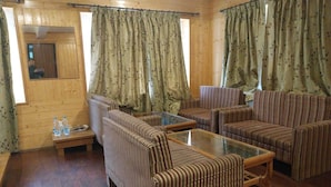 A cozy living room with striped sofas, a glass coffee table, and curtains with a floral pattern. - Hotel Mountview Sonamarg (Gund)