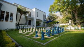 A courtyard with a chessboard, a white building, and trees. - Kilima Franschhoek  (Franschhoek)