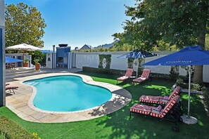 Una piscina al aire libre, sombrillas, sillones reclinables de piscina