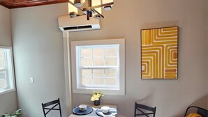 A dining area with a table, chairs, a chandelier, a window, and a wall art piece. - Historic & Chic apartment by Arena, University, Hospital - Dog Friendly (Huntington)