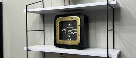 Une étagère en métal blanc ornée d’un coq décoratif, d’une horloge et d’une maquette de vélo.