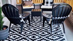 A covered patio with a checkered rug, black and white chairs, a wooden bench, and a welcome sign. - Historic & Chic apartment by Arena, University, Hospital - Dog Friendly (Huntington)