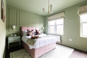 A bedroom with a bed, bedside tables, a window, and a chandelier. - Emerald Park - Hot Tub & Games Room (Scarborough)
