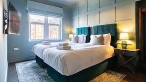 A hotel room with a bed, a window, a nightstand, and a lamp.