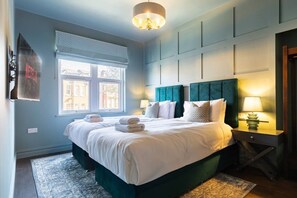 Et hotelværelse med seng, vindue, et natbord og en lampe.