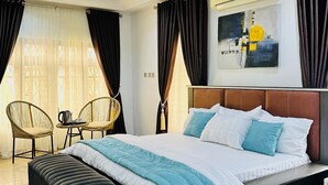 Ein modernes Schlafzimmer mit einem großen Bett, zwei Sesseln, einem Couchtisch und einem Bild an der Wand.