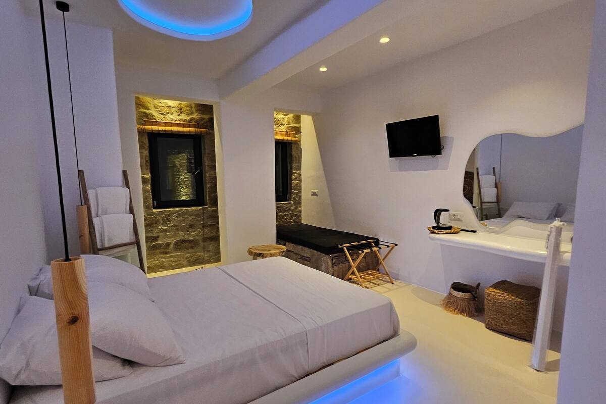 A modern bedroom with a bed, a TV, and a stone wall.