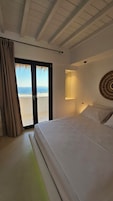 Un dormitorio con una cama grande, vistas al exterior por una puerta corrediza, un aplique de pared y una decoración de pared tejida.