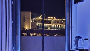 A balcony with a view of a cityscape at night, featuring illuminated buildings and a body of water. - Elli Tropical Suites  (Mykonos)