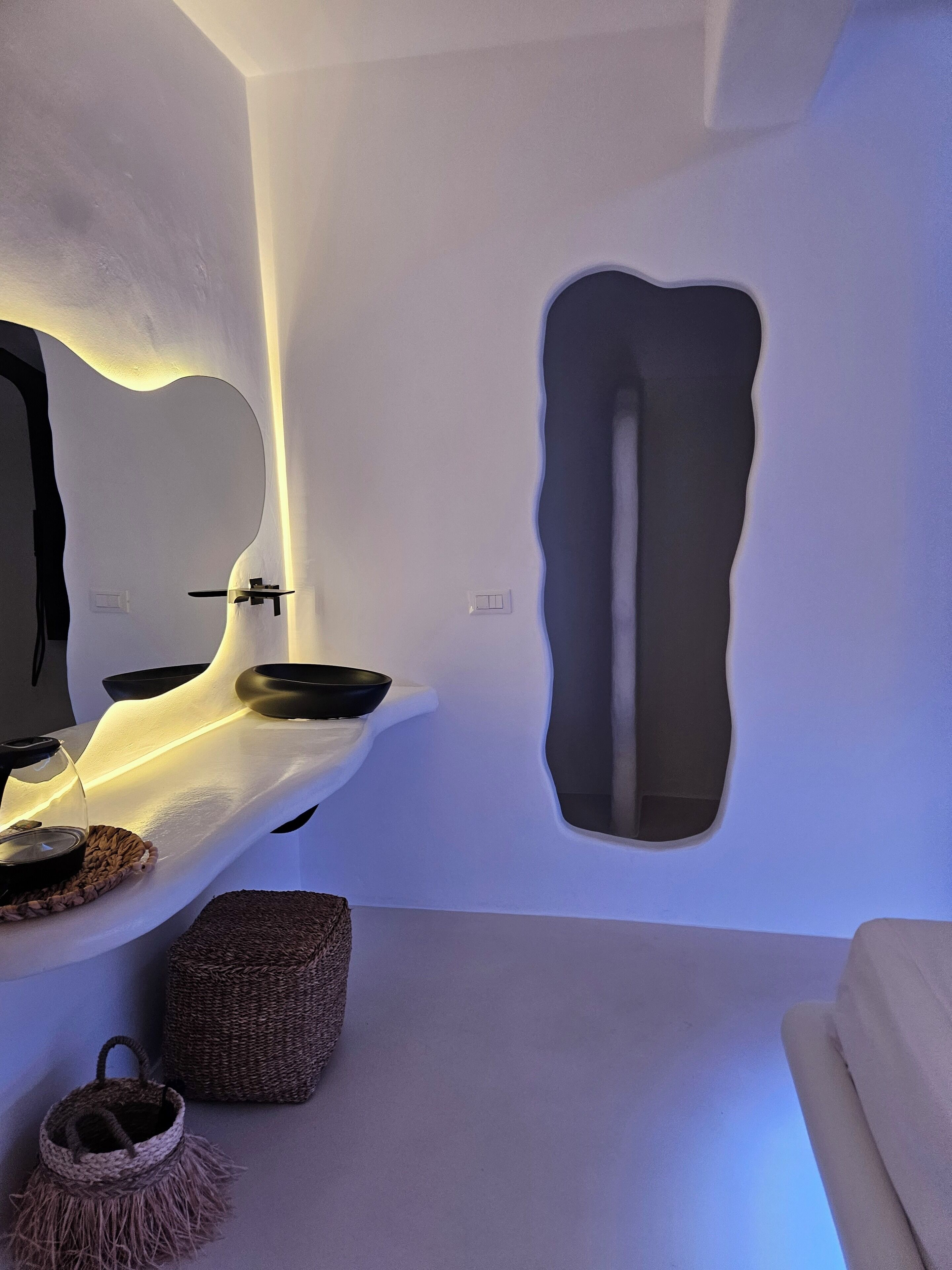 A modern bathroom with a unique sink design, a mirror, and a textured wall.