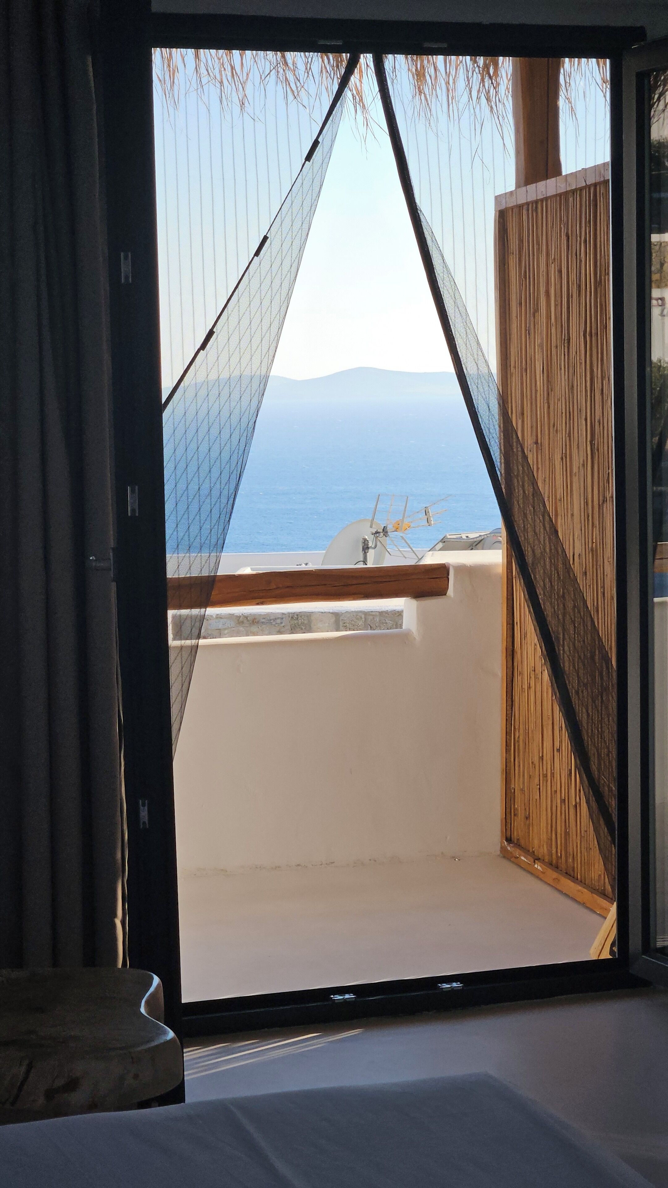 A room with a view of the sea, a wooden door, and a white wall.