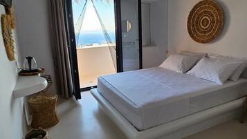 Un dormitorio con una cama, vistas a través de un ventanal y un adorno de pared tejido.