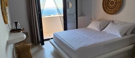 Un dormitorio con una cama, vistas a través de un ventanal y un adorno de pared tejido.