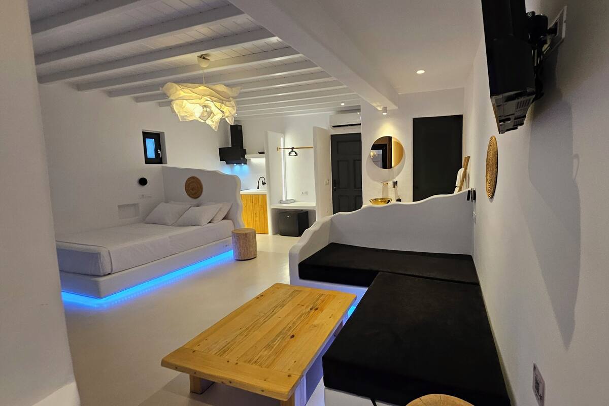 A modern living room with a white sofa, a wooden coffee table, and a black sectional sofa.