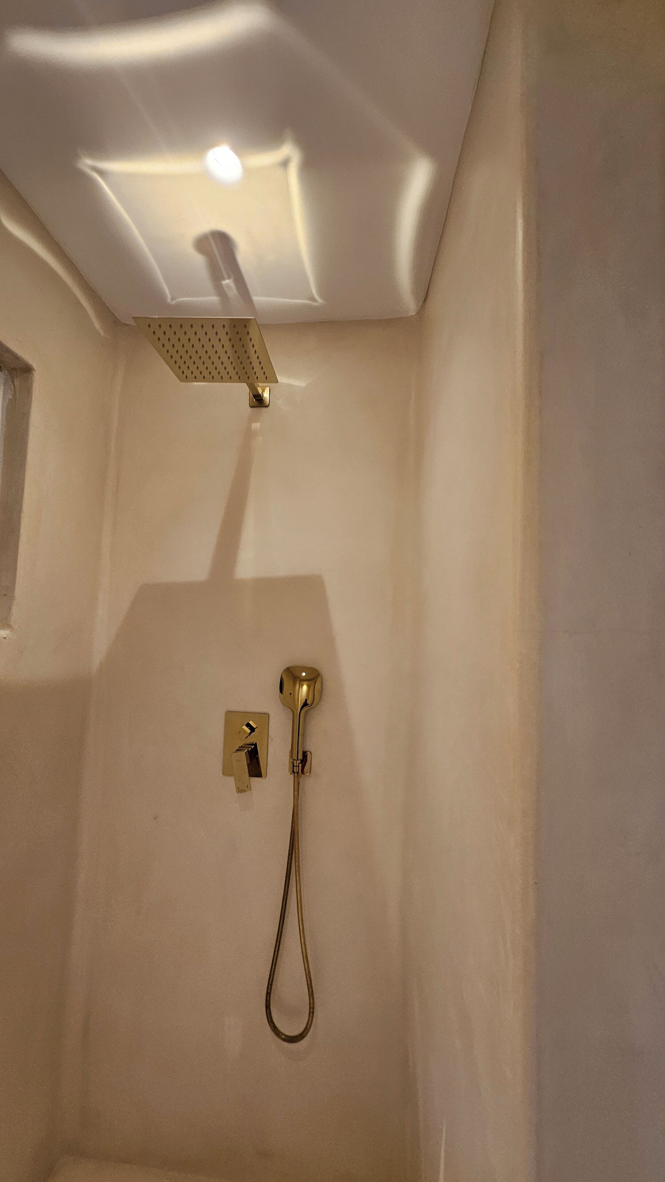Un baño con ducha, una lámpara y un panel de control en la pared.