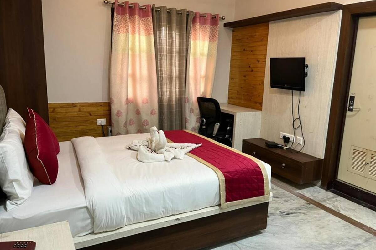 A hotel room with a bed, a desk, a chair, a TV, and a wardrobe.