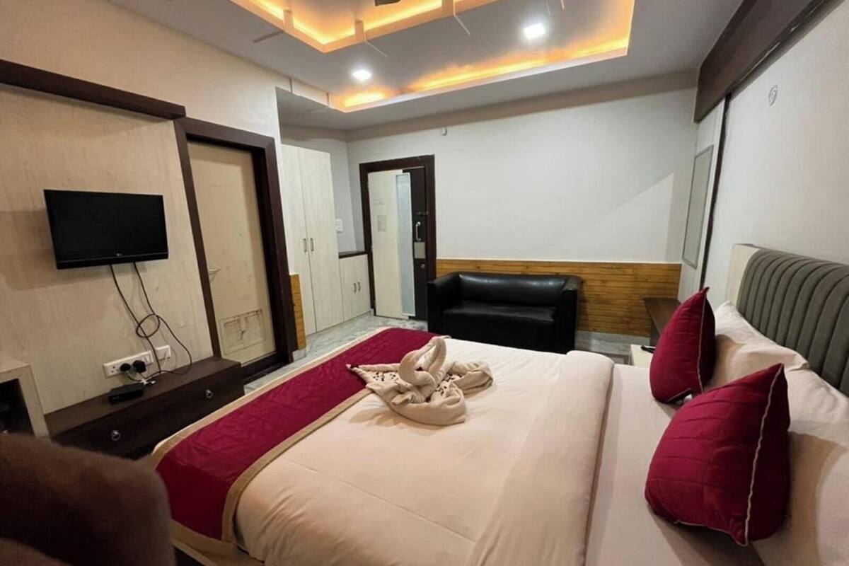 A hotel room with a bed, a television mounted on the wall, and a wardrobe.