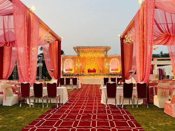 An outdoor event space with a stage, red carpet, and rows of chairs.